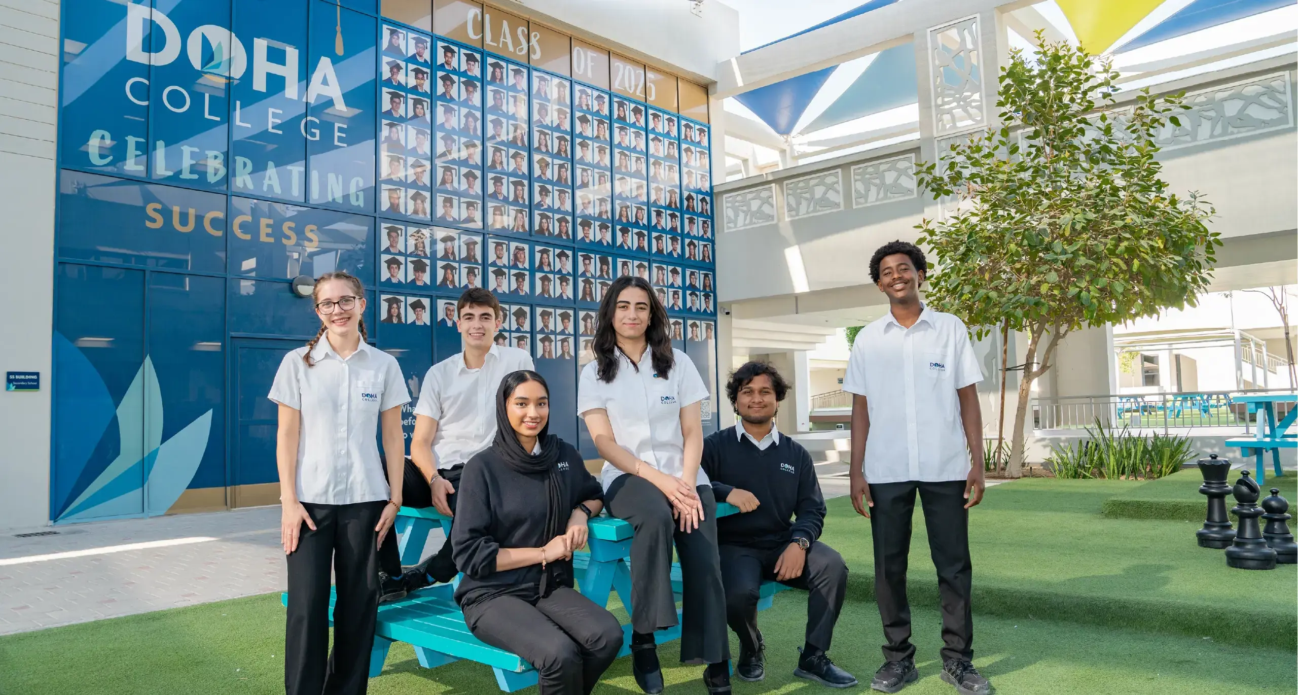 Students Posing in Front of Graduating Class Poster in Courtyard
