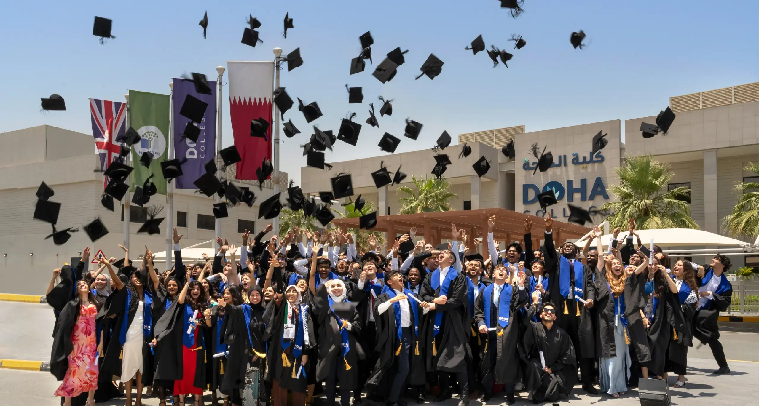 Graduating Students Throwing Graduation Caps in Front of Campus